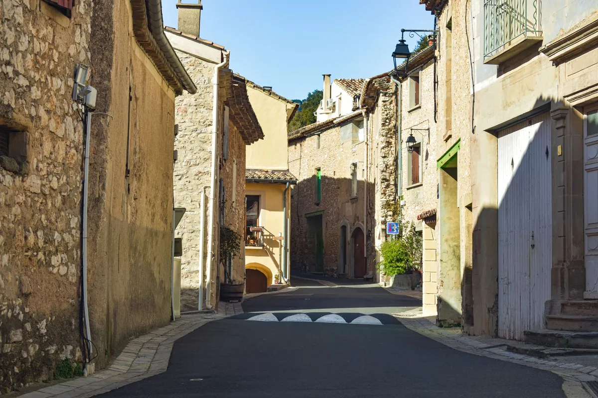 A narrow stone village lane in Provence lined with shuttered houses and potted plants